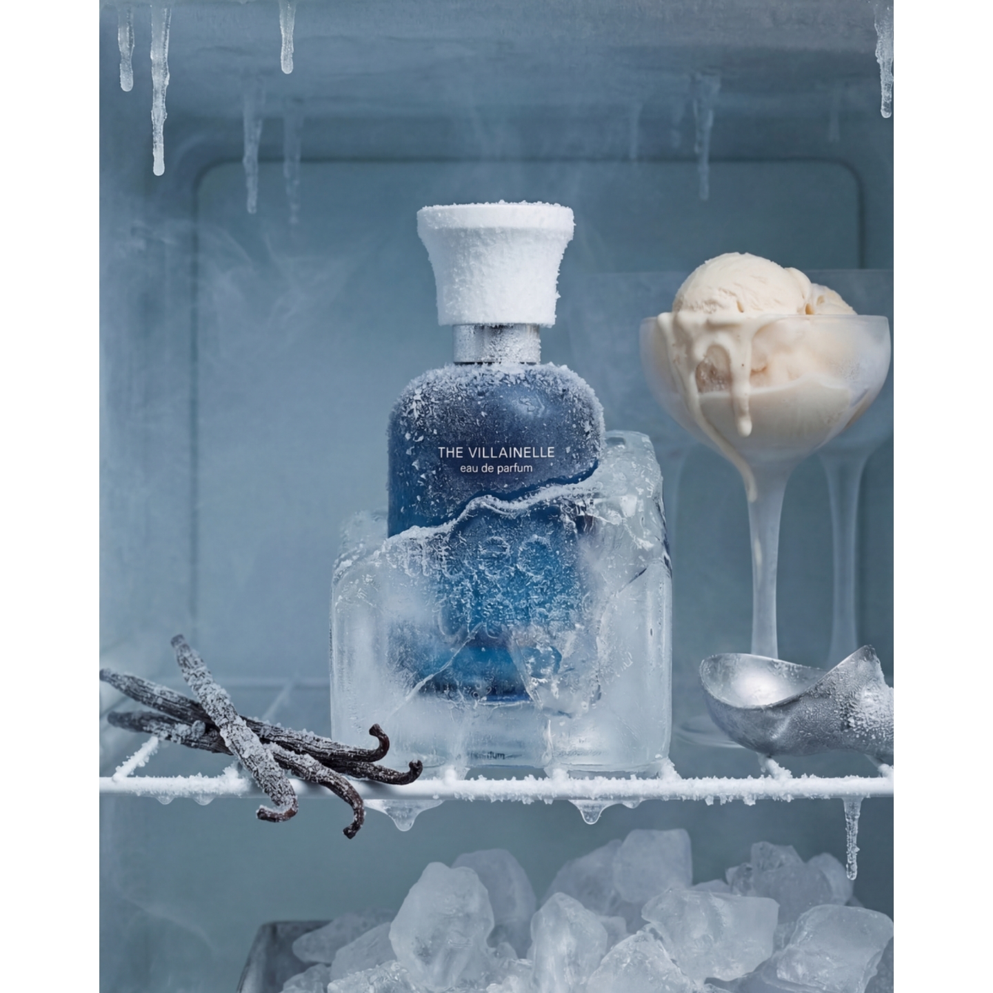 A frosted blue bottle of Anecdotes by Artists The Villainelle Eau de Parfum encased in ice on a freezer shelf next to vanilla pods, ice cream, and an ice scoop.