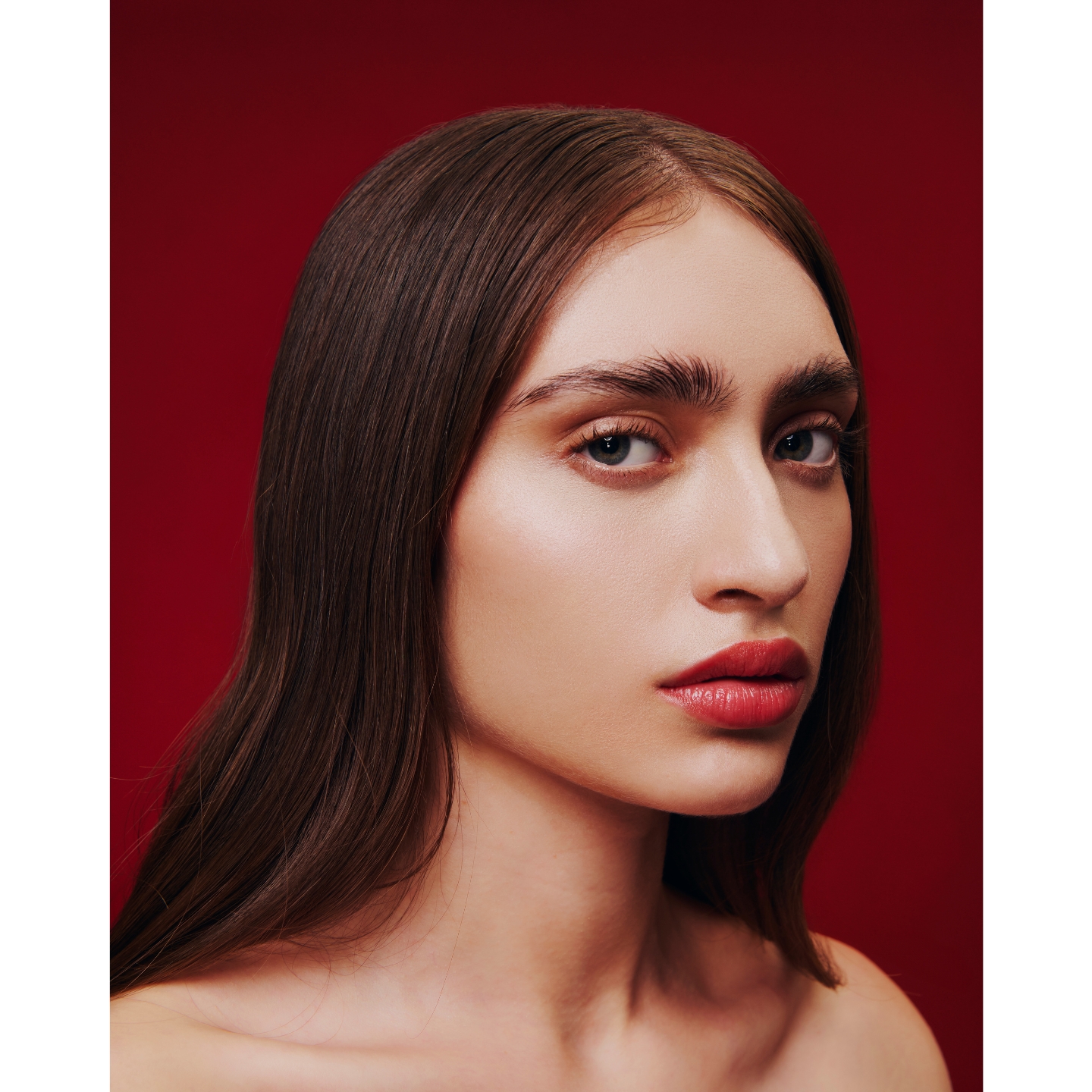 A model showcasing a clean makeup look with bold red lips against a deep red background, featured in the Aora México Sephora launch announcement on Beauty News Daily.