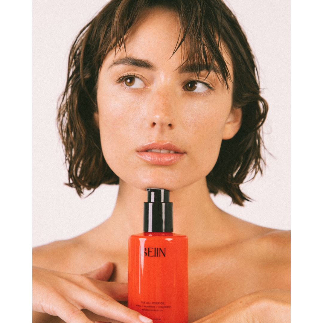 A model with a wet bob holds a bottle of Beiin The All-Over Oil beneath her chin