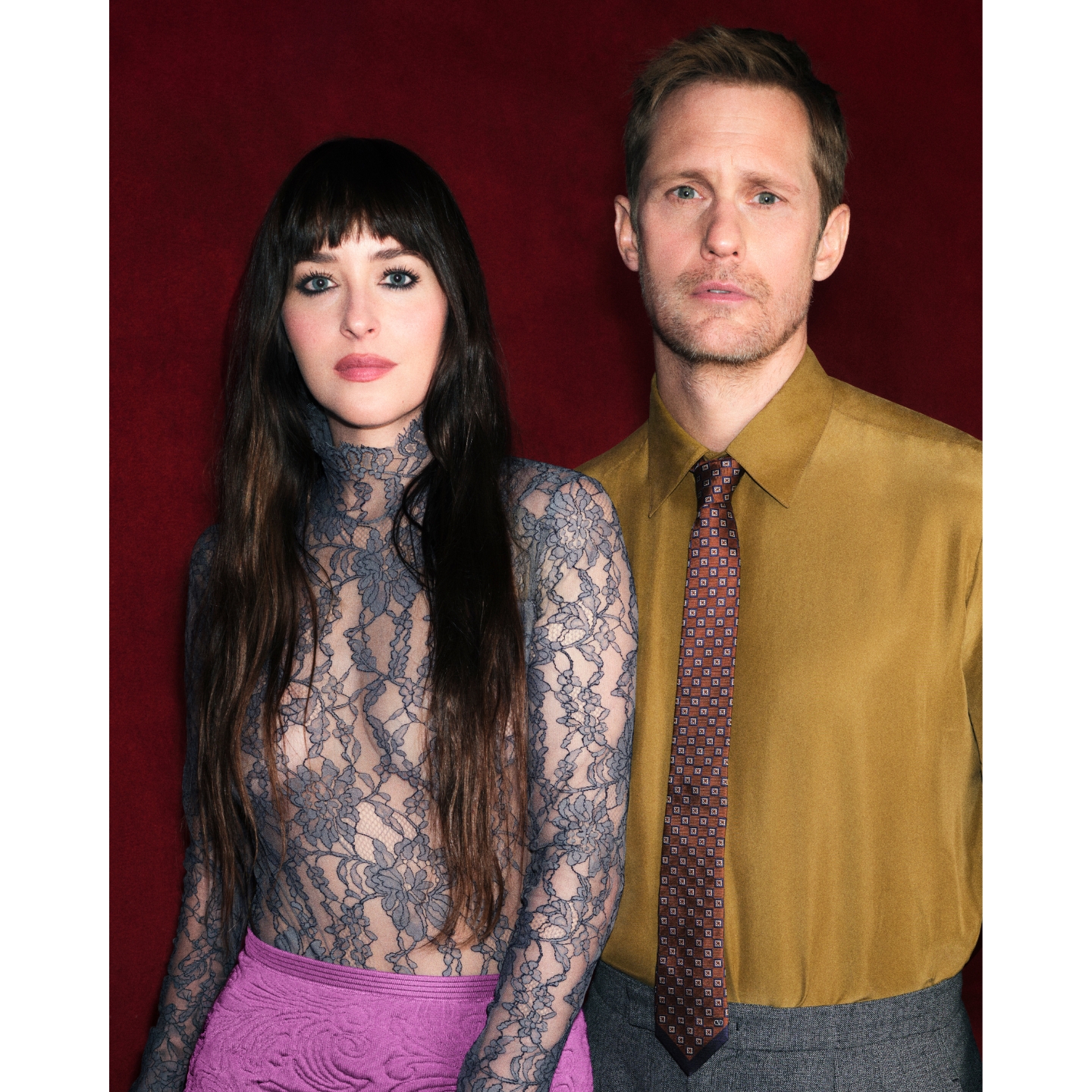 Dakota Johnson in a grey lace top and Alexander Skarsgård in a mustard gold shirt posing together for Valentino Beauty, featured on Beauty News Daily.