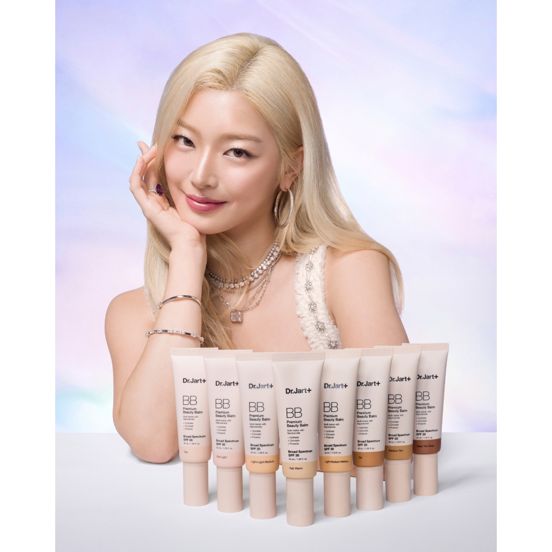 Katseye’s Yoonchae poses behind a row of Dr.Jart+ Premium BB Cream SPF 30 tubes in eight shades, against a soft pastel backdrop