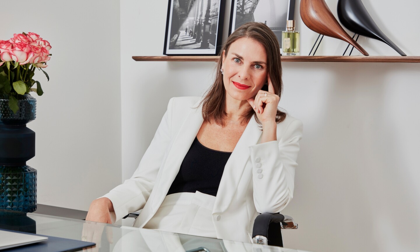 Ex Nihilo co-founder Sylvie Loday wearing a white pantsuit and red lipstick, featured in her interview on Beauty News Daily.