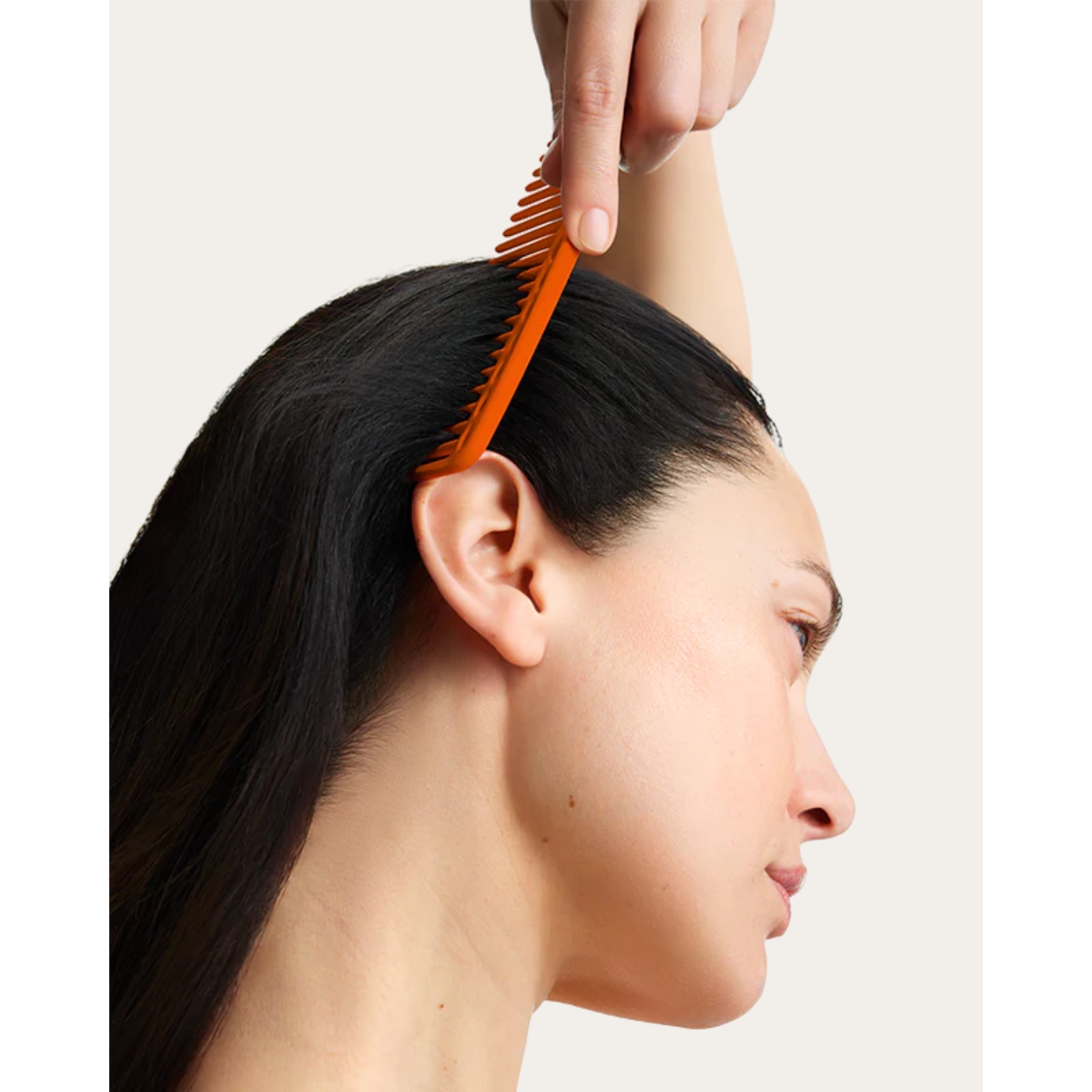 Model using an orange comb through her dark hair, featured in the Loya haircare range launch on Beauty News Daily.