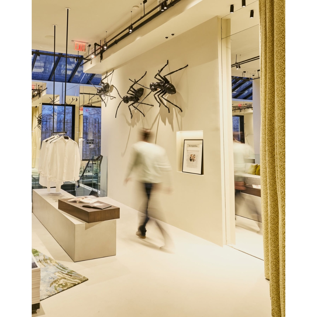 Interior of the Marc-Antoine Barrois New York flagship store featuring minimalist neutral decor, clothing displays, and large black ant sculptures mounted on the wall.