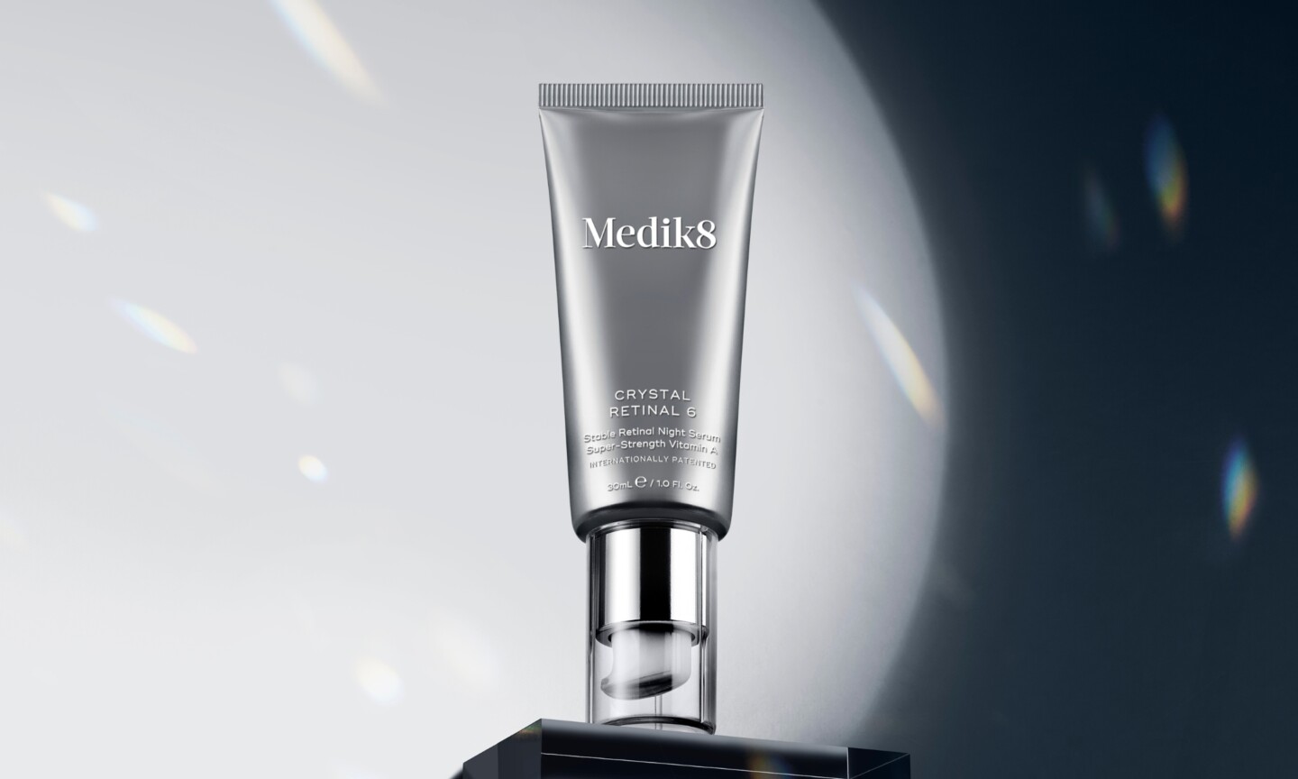 A metallic tube of Medik8 Crystal Retinal 6 Stable Retinal Night Serum displayed on a black block under a bright spotlight, featured in the brand's Sephora US launch announcement on Beauty News Daily.