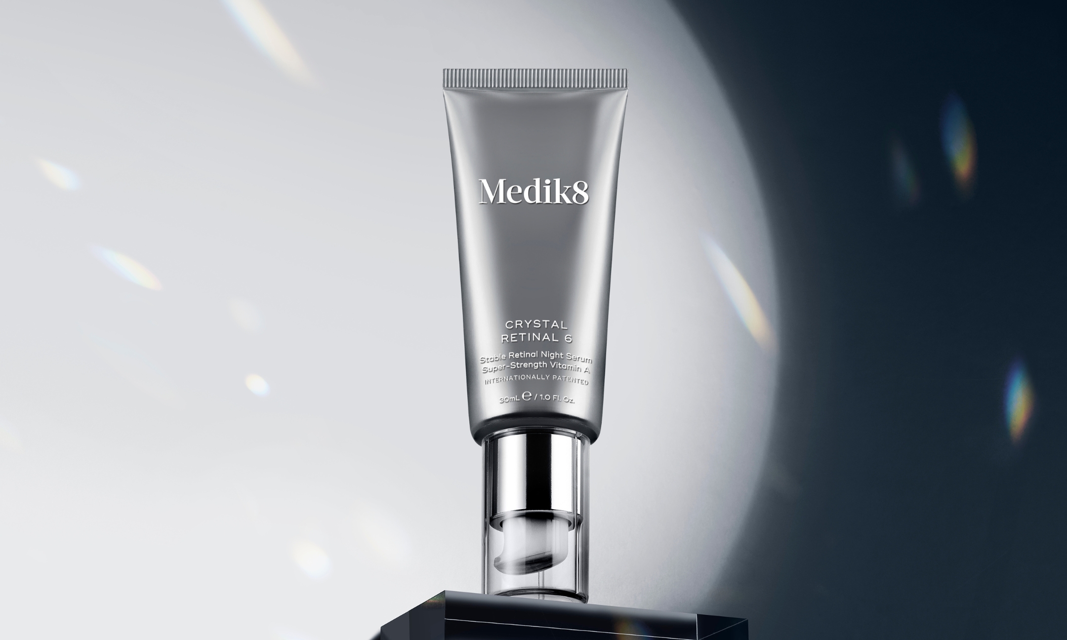 A metallic tube of Medik8 Crystal Retinal 6 Stable Retinal Night Serum displayed on a black block under a bright spotlight, featured in the brand's Sephora US launch announcement on Beauty News Daily.
