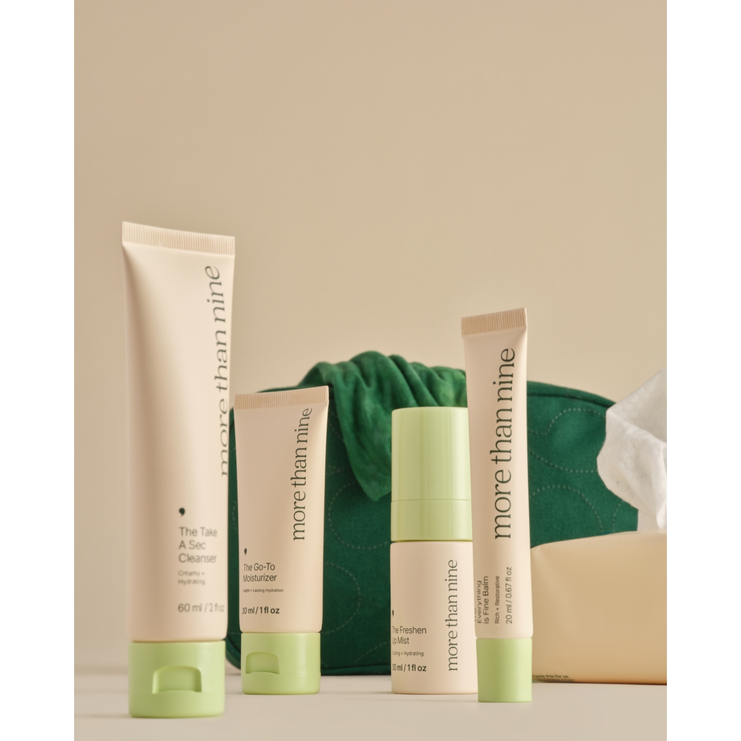 An array of More Than Nine skincare products in beige packaging with light green caps, including The Take A Sec Cleanser, The Go-To Moisturizer, The Freshen Up Mist, and Everything Is Fine Balm, set against a green makeup bag.