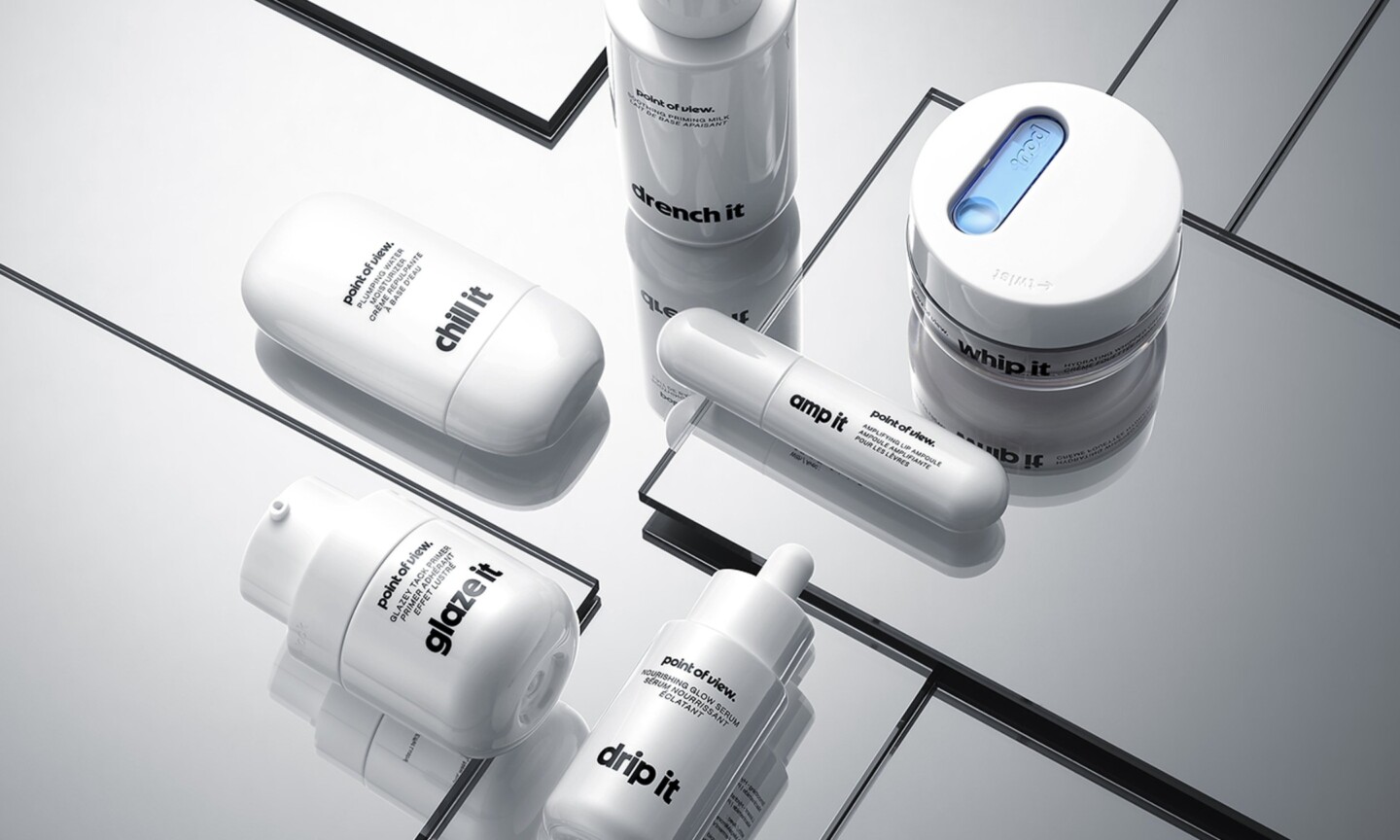 White Point of View skincare bottles, jars and tubes arranged on mirrored glass.