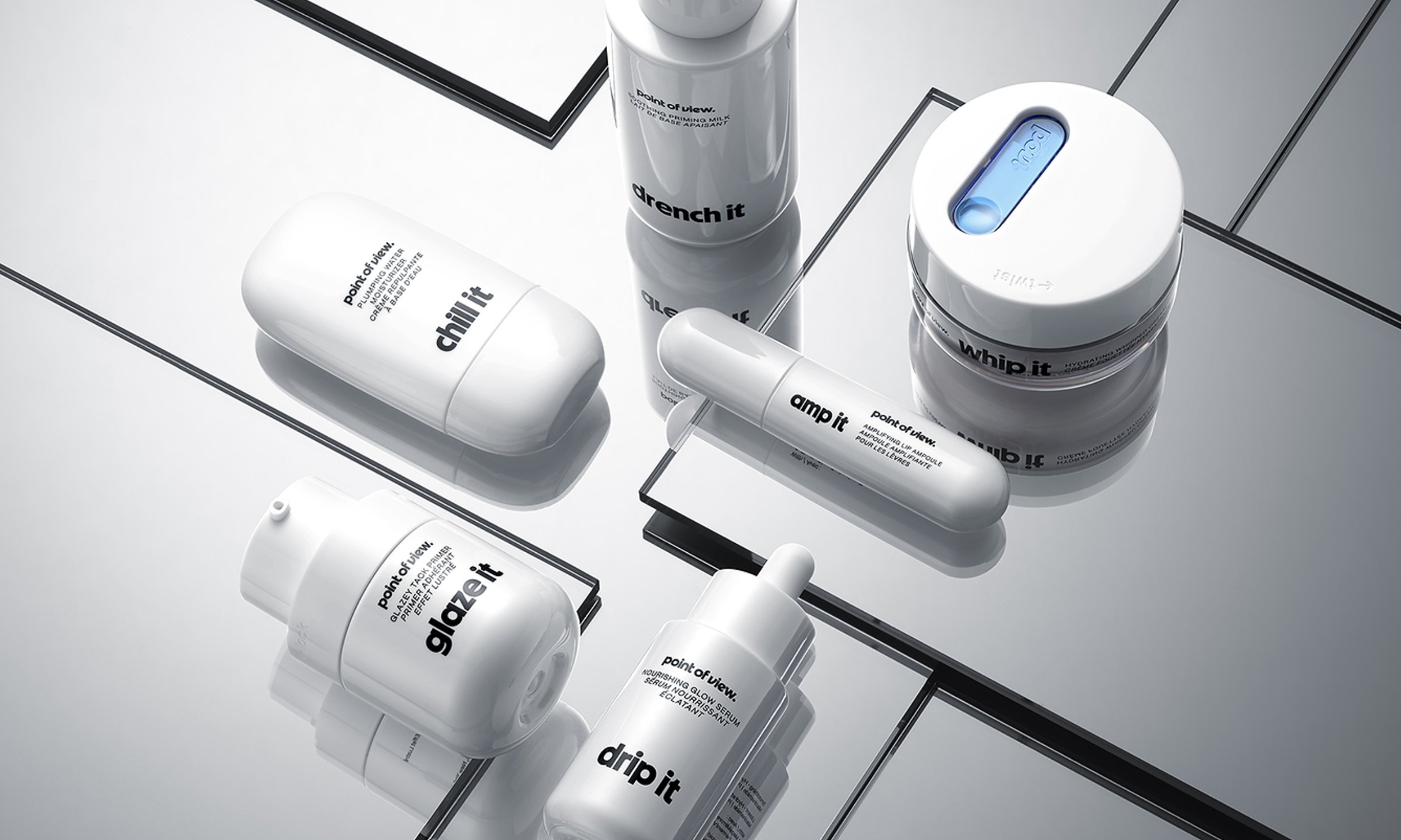 White Point of View skincare bottles, jars and tubes arranged on mirrored glass.