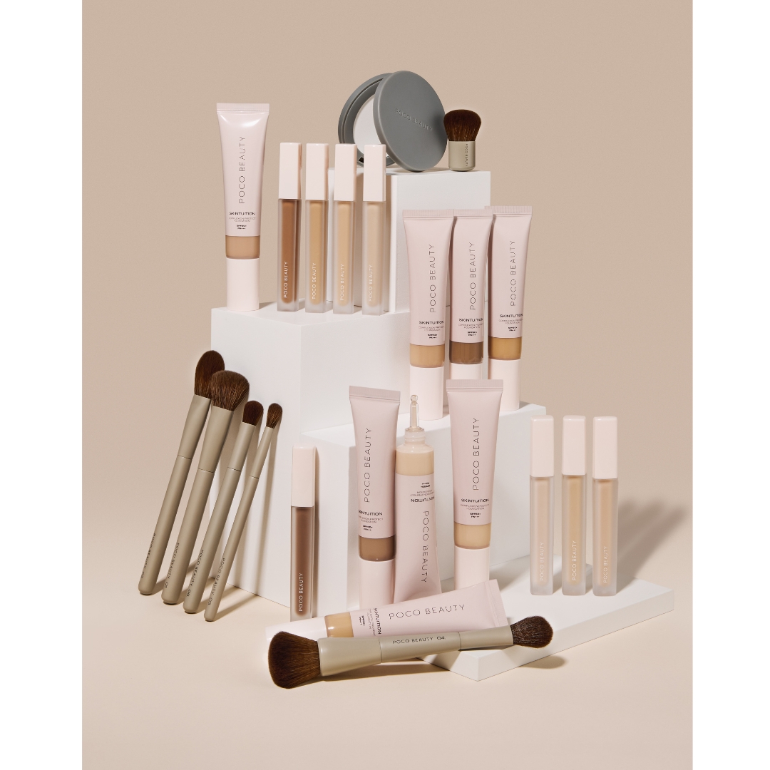 An organised display of Poco Beauty makeup products, including liquid foundations, concealers, compact powders, and makeup brushes on white pedestals.