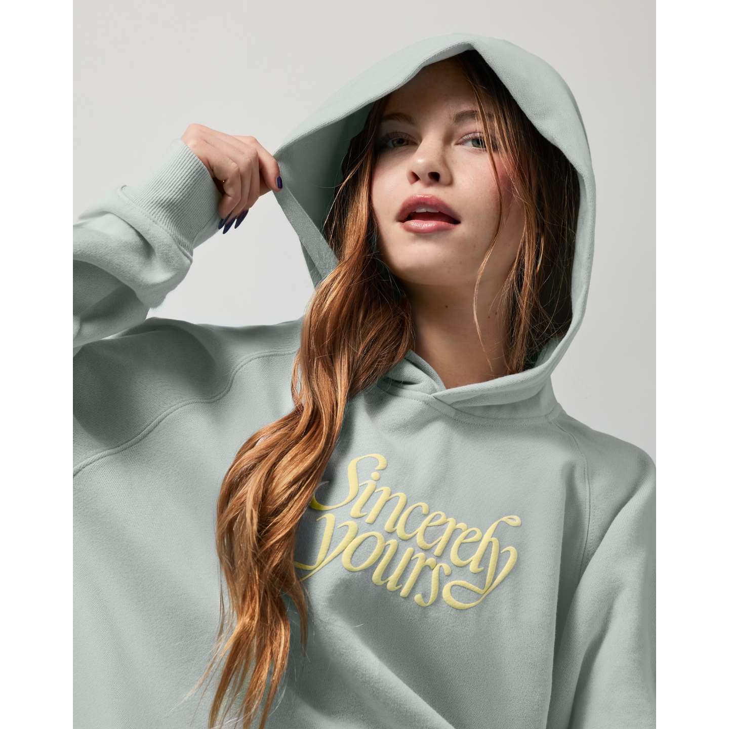 Salish Matter wearing a light grey Sincerely Yours hooded sweatshirt with yellow script text, featured on Beauty News Daily.