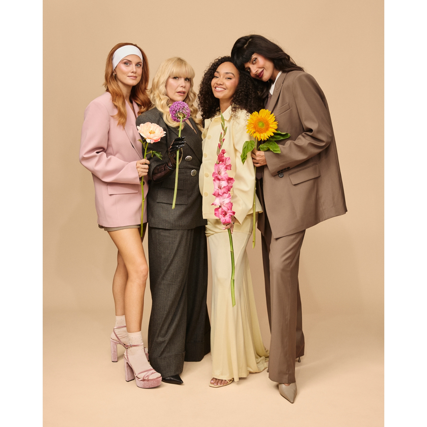 Ashley James, Paloma Faith, Leigh-Anne Pinnock, and Jameela Jamil posing together in pastel and neutral tailoring while holding flowers, featured in a daily beauty news roundup on Beauty News Daily.