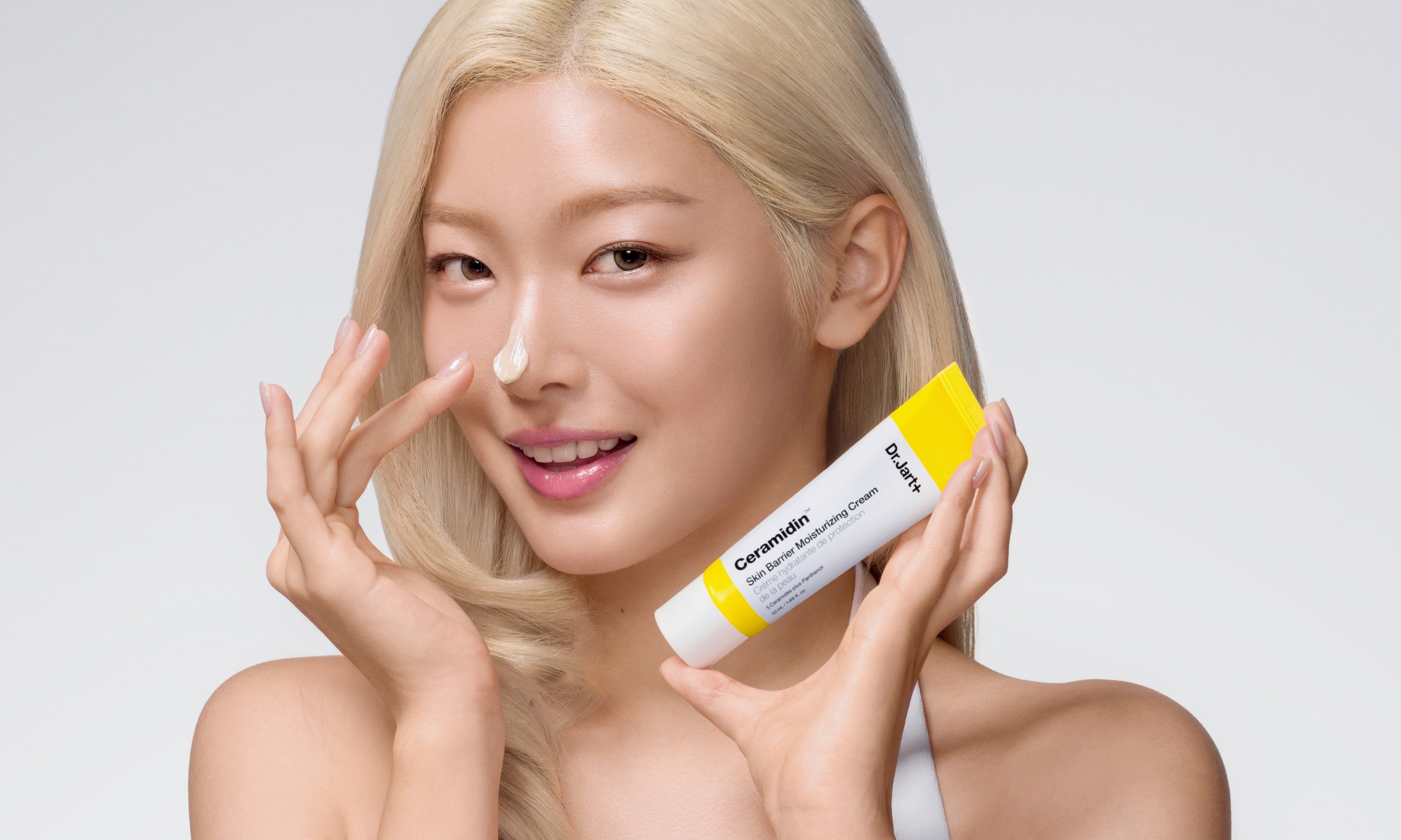 Katseye’s Yoonchae holds Dr.Jart+ Ceramidin Skin Barrier Moisturizing Cream, with a dab of cream on her nose